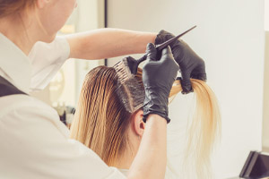 Stylist applying dye to blend a woman's roots
